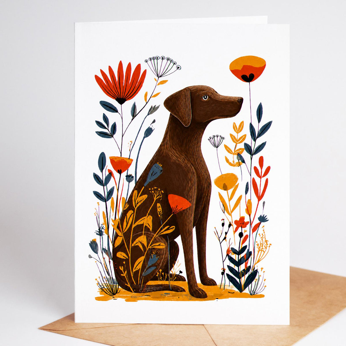 Chocolate Lab card standing on a kraft envelope, a brown Labrador sitting among red, orange and navy folk art flowers