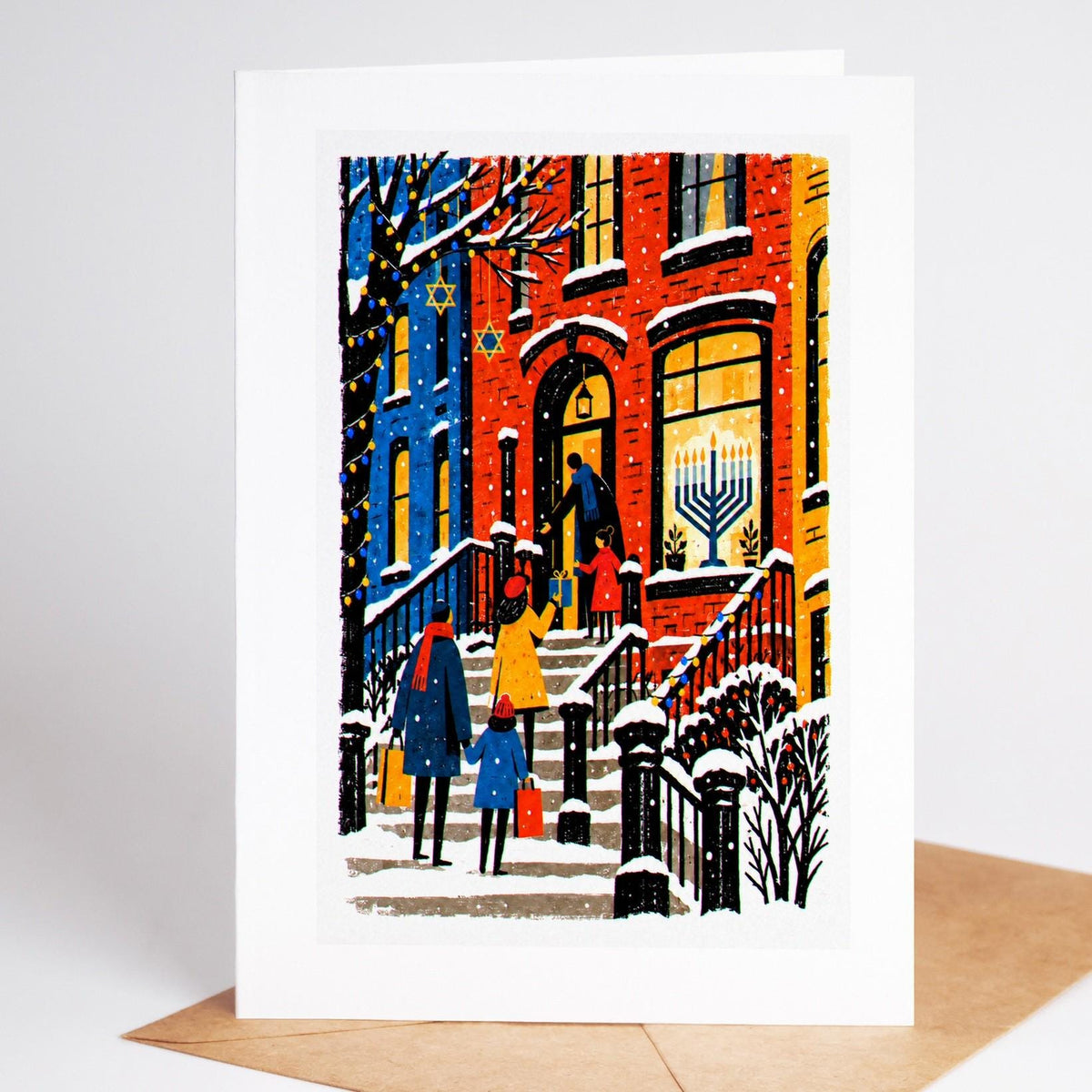 New York Hanukkah card standing with envelope, a family on a snowy brownstone stoop with a menorah in the window