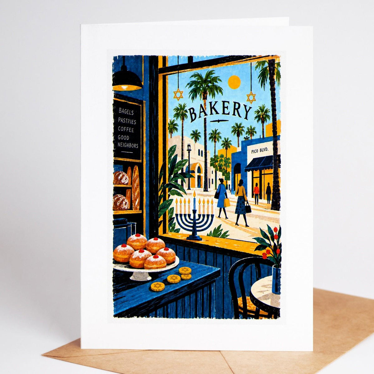 Los Angeles Hanukkah card standing upright, a Pico Boulevard bakery window with sufganiyot and a lit menorah