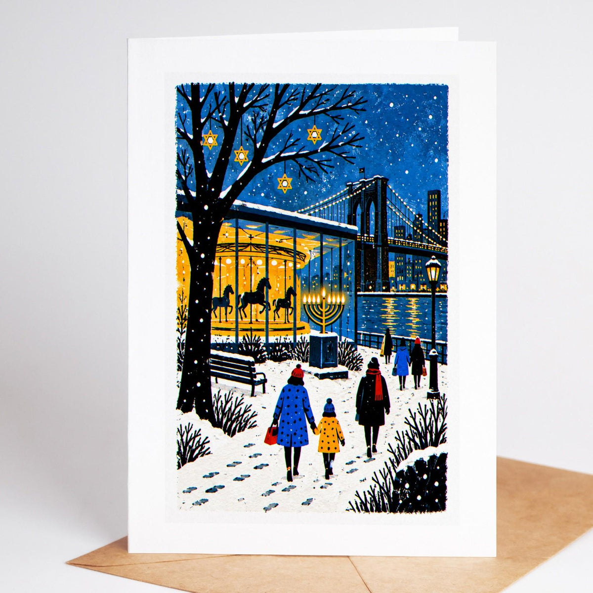 Brooklyn Hanukkah card standing upright, Jane's Carousel lit at night below the Brooklyn Bridge with a menorah alongside