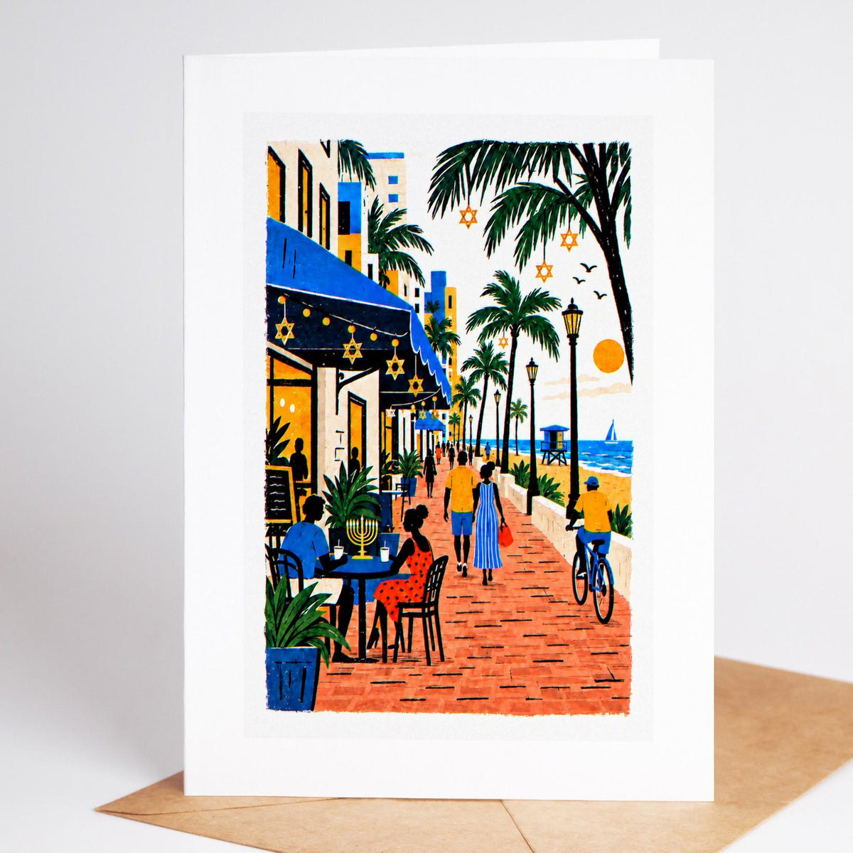 South Florida Hanukkah card standing with envelope, a Hollywood Beach cafe on the broadwalk with a menorah on the table